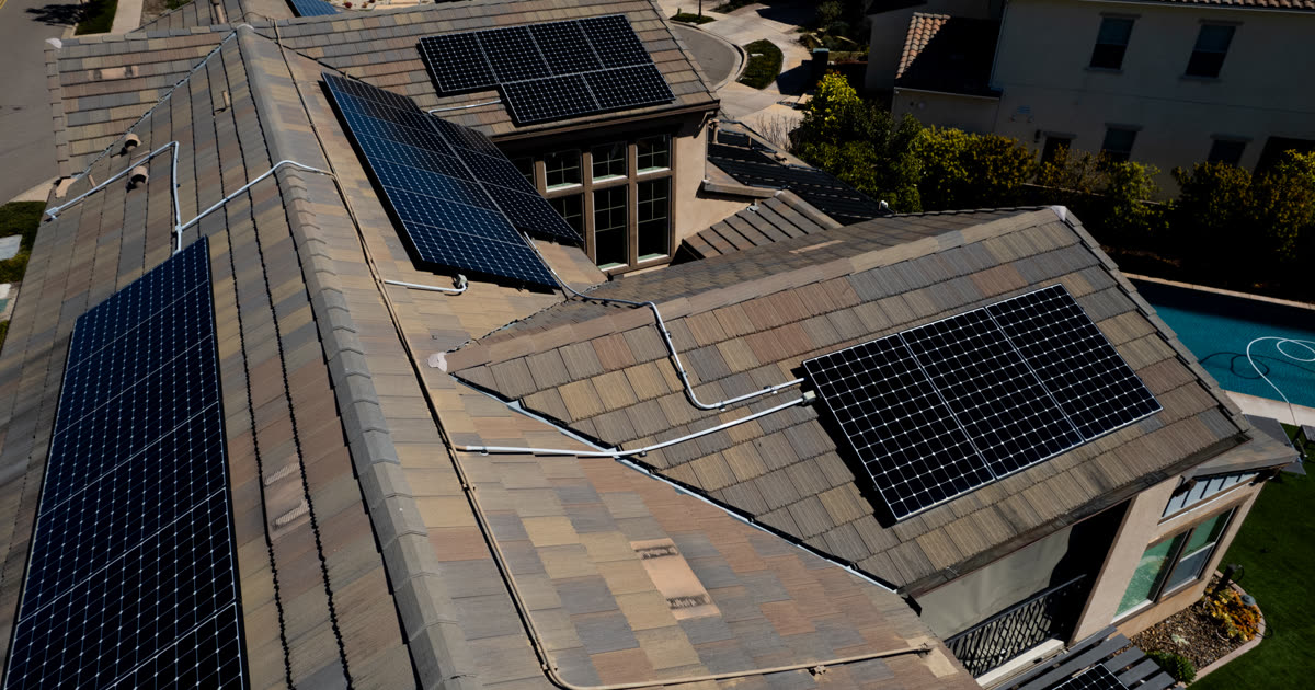 Oblique aerial view of a residential roof with multiple solar panel arrays