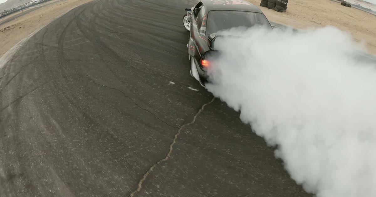 Black drift car producing a wall of tire smoke during an FPV chase